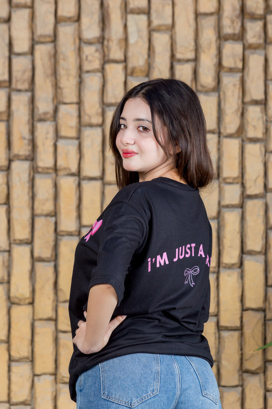 Woman wearing a black t-shirt with text, standing against a stone wall.